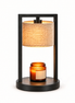 Morven Scrim candle warmer lamp with a cream linen shade, lit, on a plain background