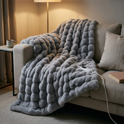 Morven Wrap heated throw over a sofa in a living room at night