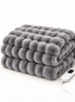 Morven Wrap heated throw in grey, folded with its controller, on a plain background